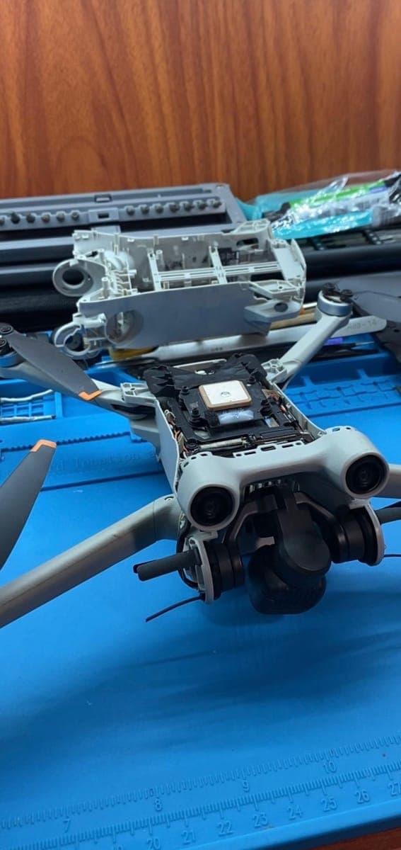 Close-up of a DJI drone opened up for repair, showing the GPS module and gimbal