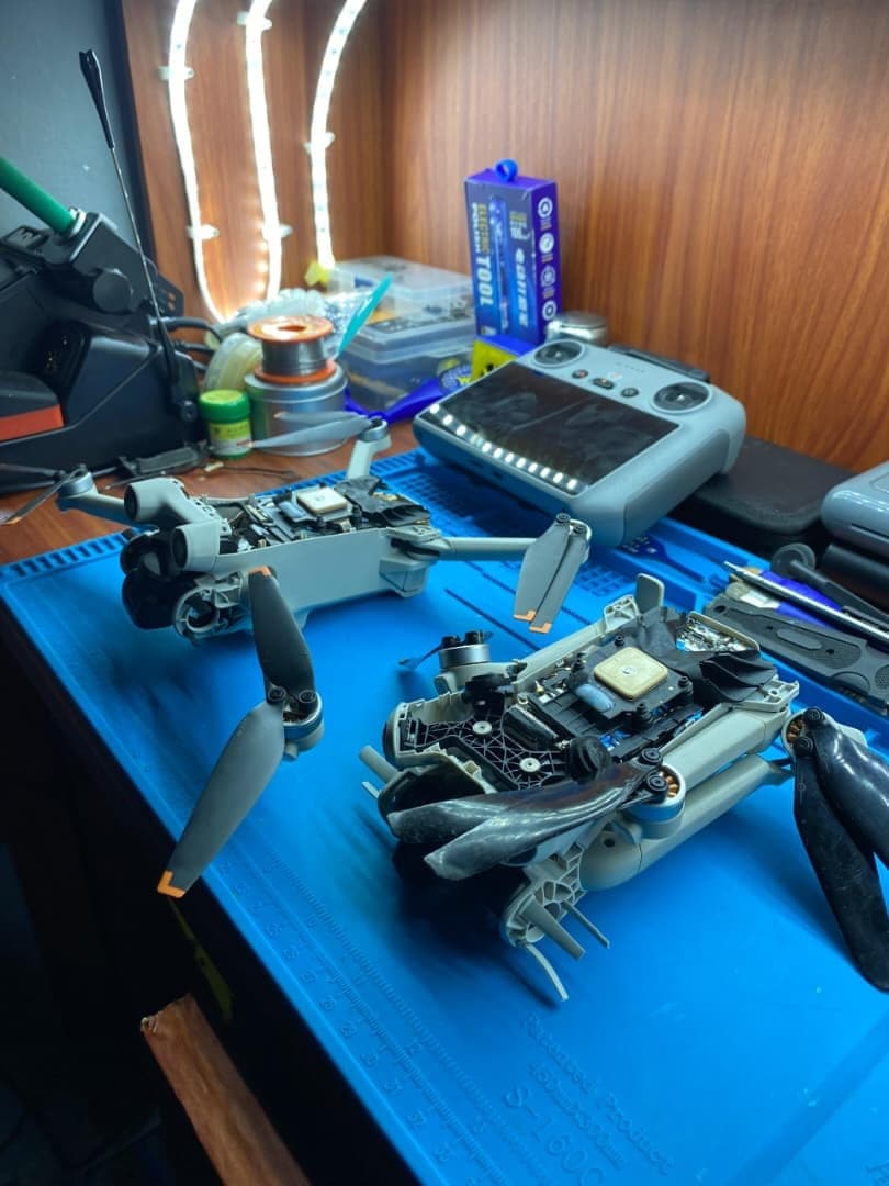 Two DJI drones being serviced on an anti-static repair mat